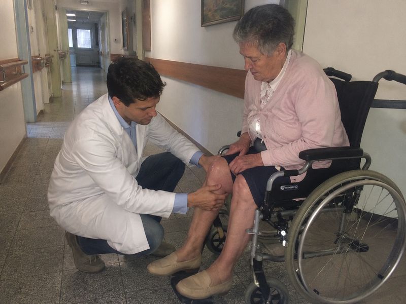 Dr. Marco Branco examina o joelho de uma paciente num lar de idosos